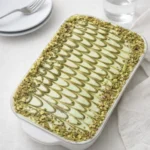 A delicious dish of Pistachio Tiramisu with green cream swirls and crushed nuts.